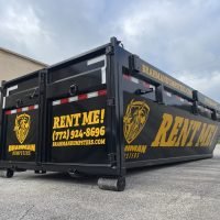 Dumpster Wrapped with Rent Me in Large Letters from a Back Angle View.
